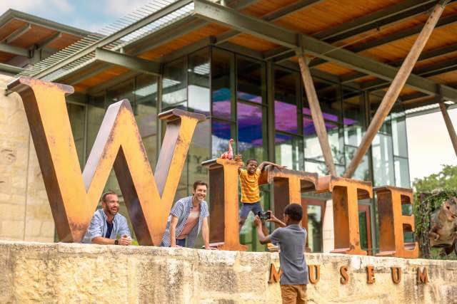 family posing outside of witte musuem signage