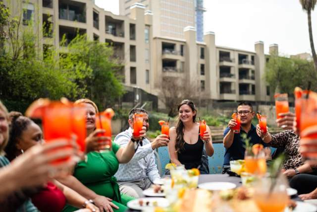 People toasting orange drinks on a river barge