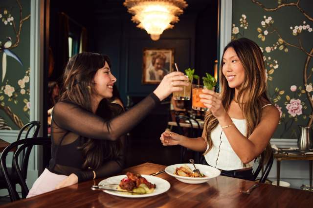 Two girls toasting their drinks