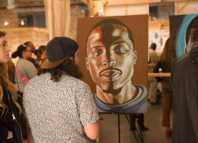 Man and woman viewing portait of a man at a gallery at DreamWeek San Antonio.