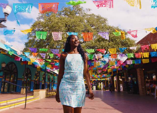 Woman walking through Historic Market Square with. papel picado in background.