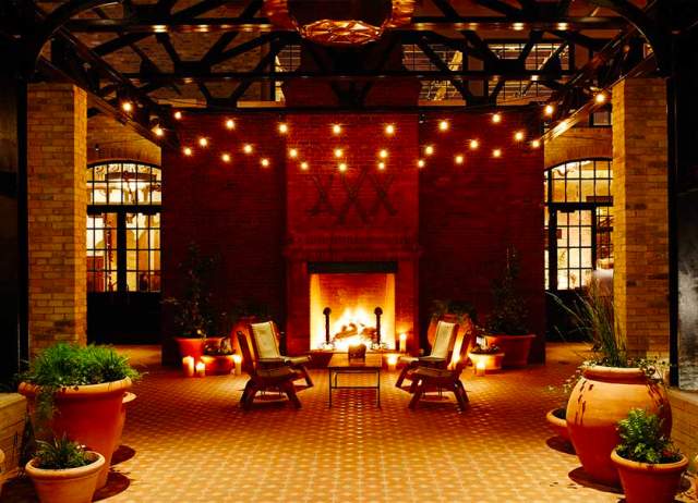 Fireplace providing ambient lighting at Hotel Emma courtyard.