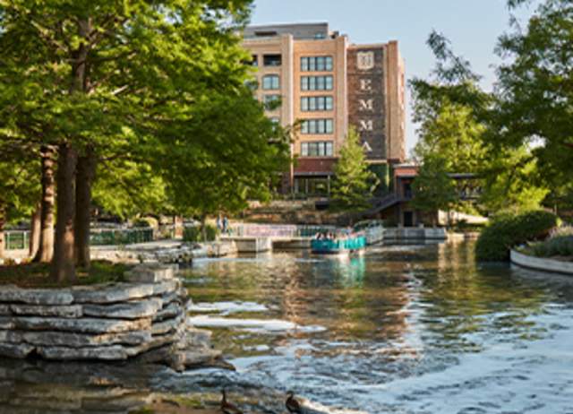 River barge on San Antonio River with Hotel Emma in background.