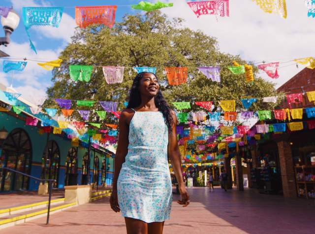 Woman walking through Historic Market Square with. papel picado in background.