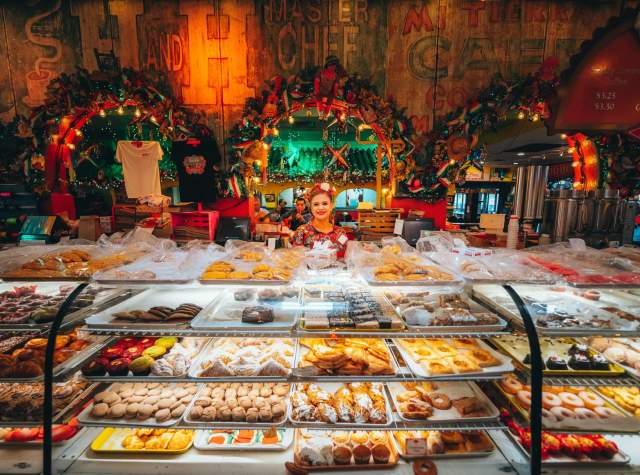 Woman standing in front of glass case of sweet Mexican pastries