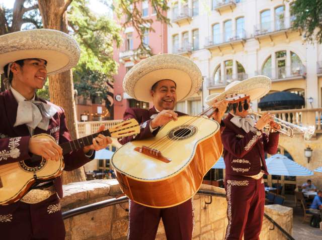 A three-member mariachi band playing music on the River Walk.