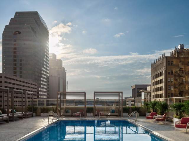 Hotel pool with sunrise and building in background.