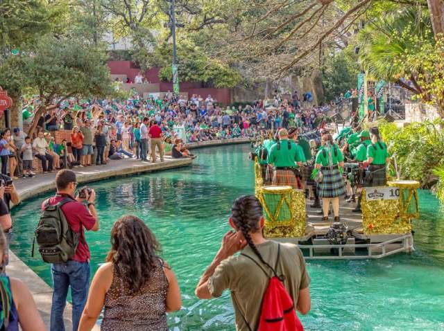Spectators gathering around river dyed green and river barge