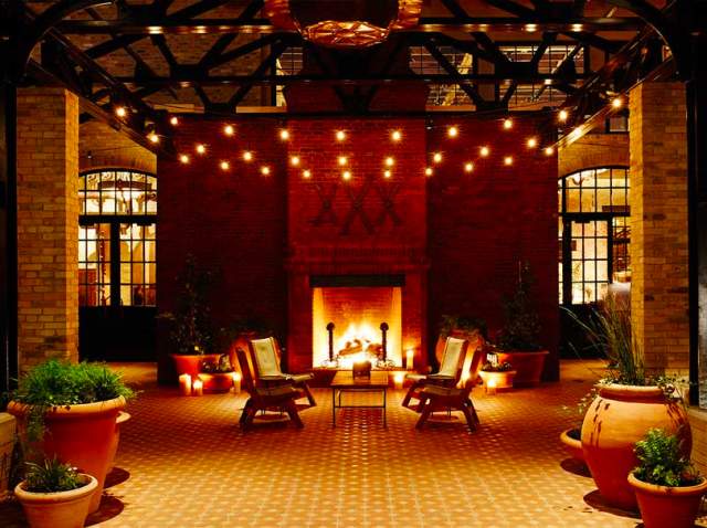 Fireplace providing ambient lighting at Hotel Emma courtyard.