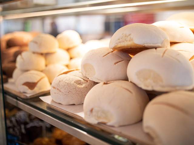 Conchas stacked on top of each other in display case at La Panaderia.