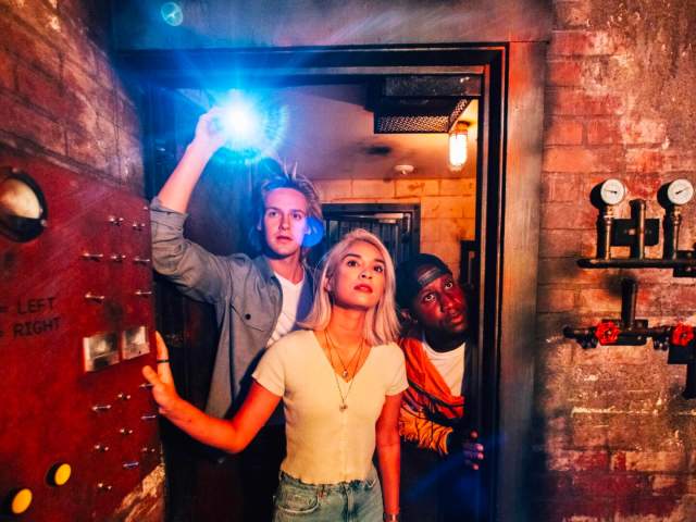 Girl and two boys opening door and holding flashlight.