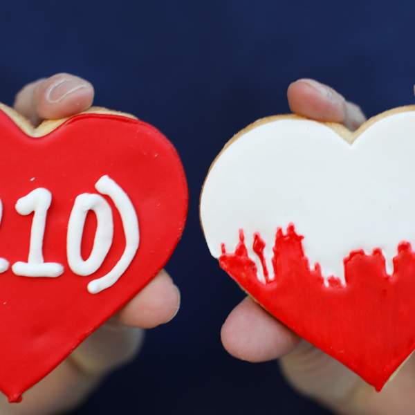Two cookies in the shape of a heart, one that is red with (210) written in white.