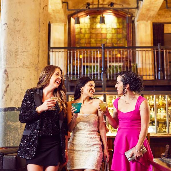 Three girls enjoying drinks in beautiful room with two large pillars