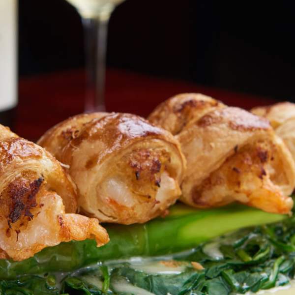 Wrapped shrimp over greens with lemon garnish
