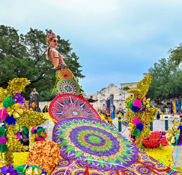 Parade participants on float dressed in elaborate dresses at Battle of Flowers parade in San Antonio in Fiesta San Antonio.