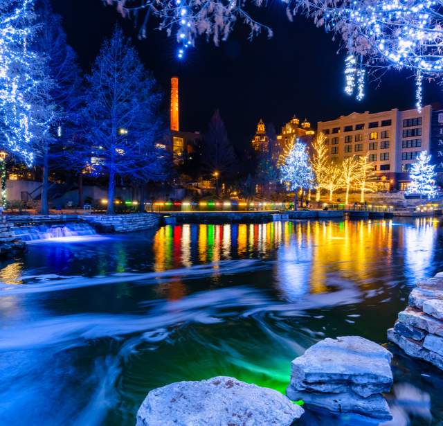 Museum Reach portion of River Walk lit up with blue-hued holiday lights.