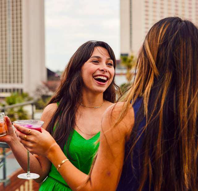 Two girls holding drinks and laughing