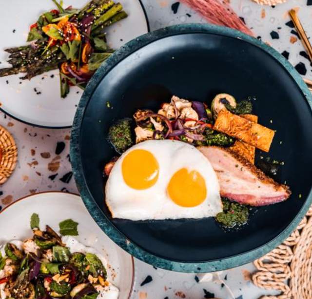Overhead view of bowl will over easy egg and side salads