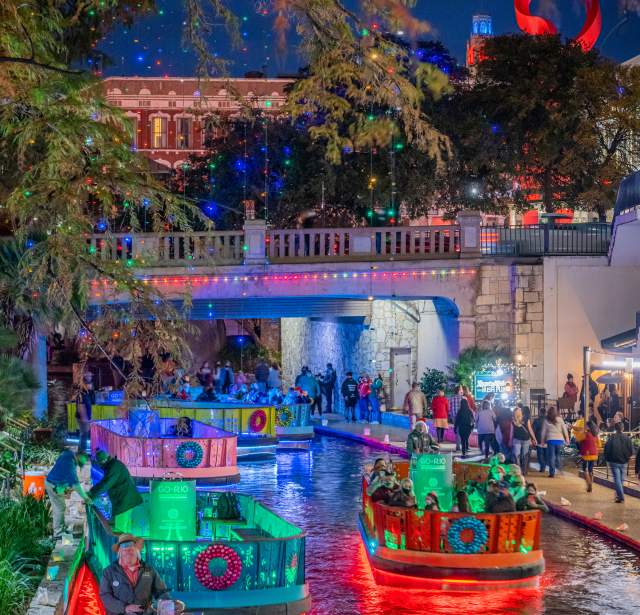 River Walk lit up with holiday lights and river barges