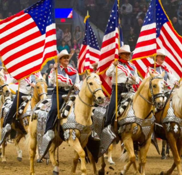 Group of riders on horses holding American flags