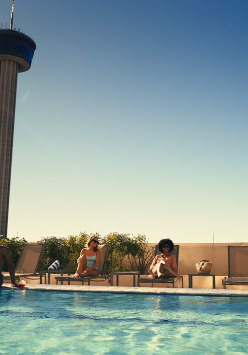 People enjoying pool with Tower of the Americas in distance