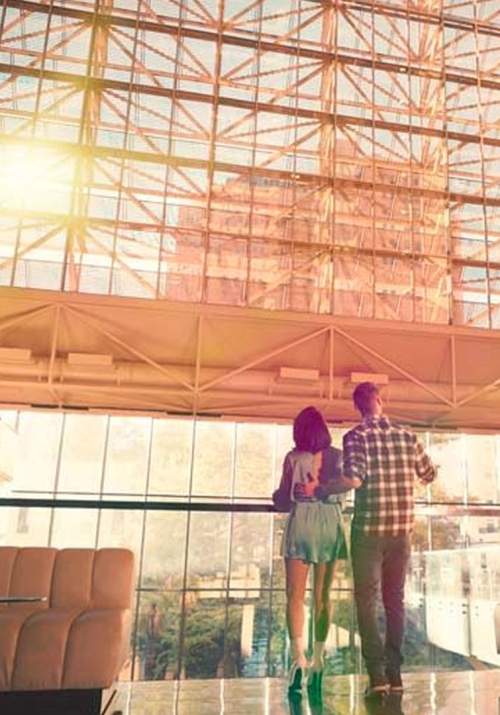 Man and woman looking at hotel lobby with bright sun shining through window.