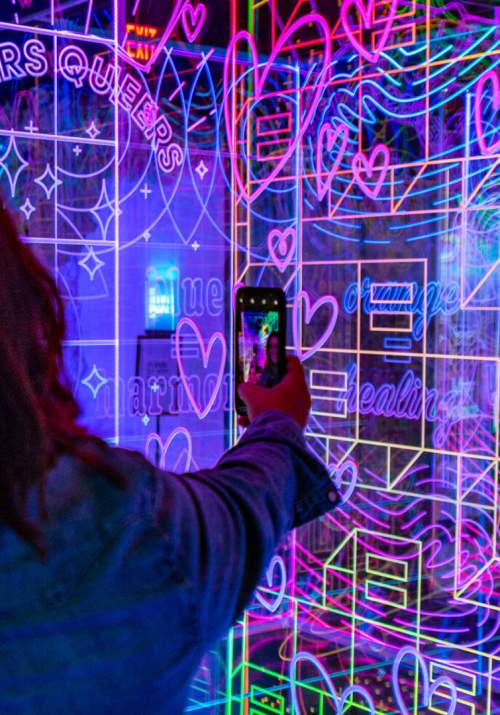 Woman taking photo with her phone of multicolored wall