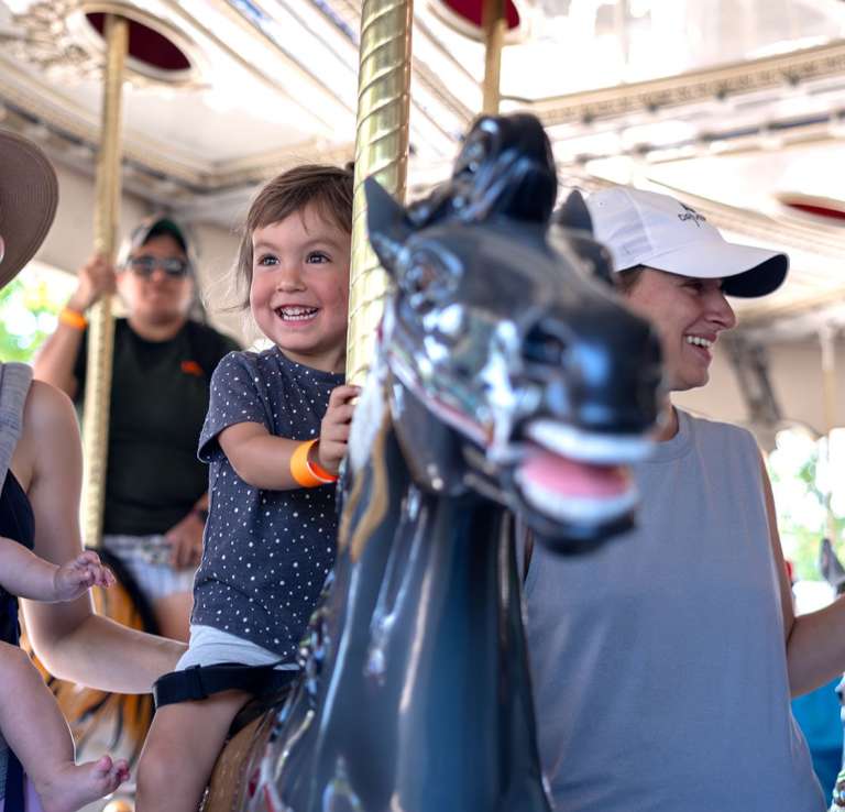 child and family on carousel ride