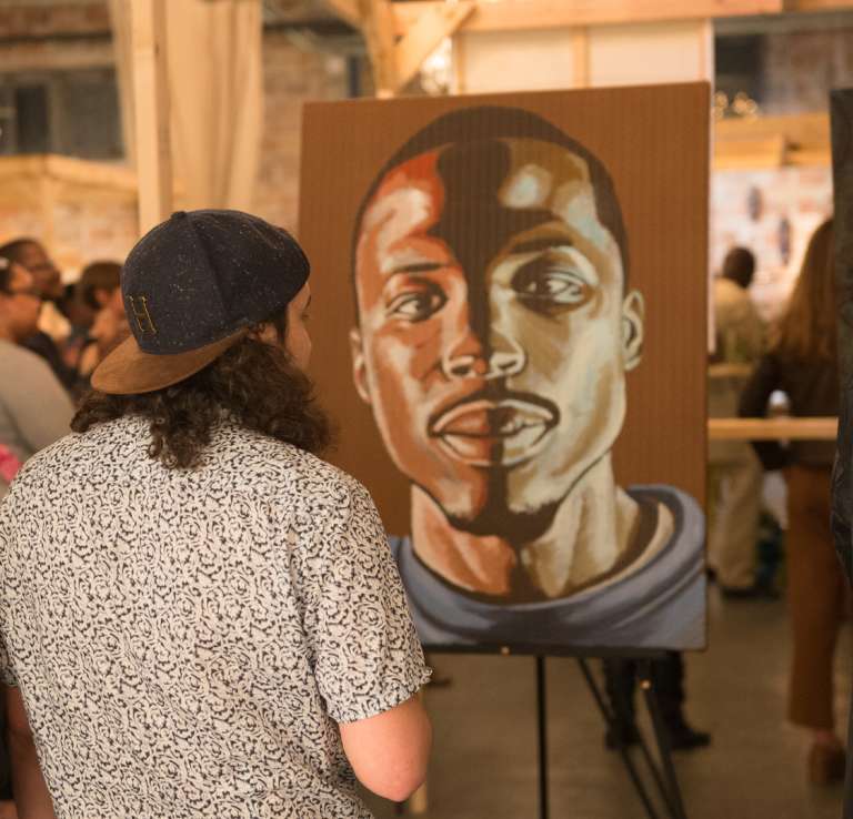 Man and woman viewing portait of a man at a gallery at DreamWeek San Antonio.