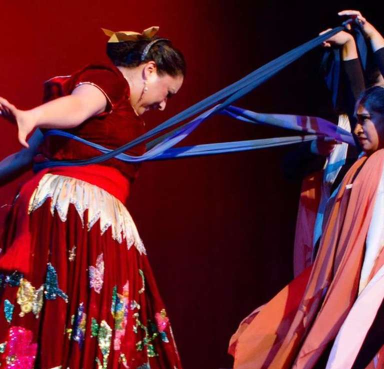 Two women in theatrical performances with cultural dresses and scarfs.
