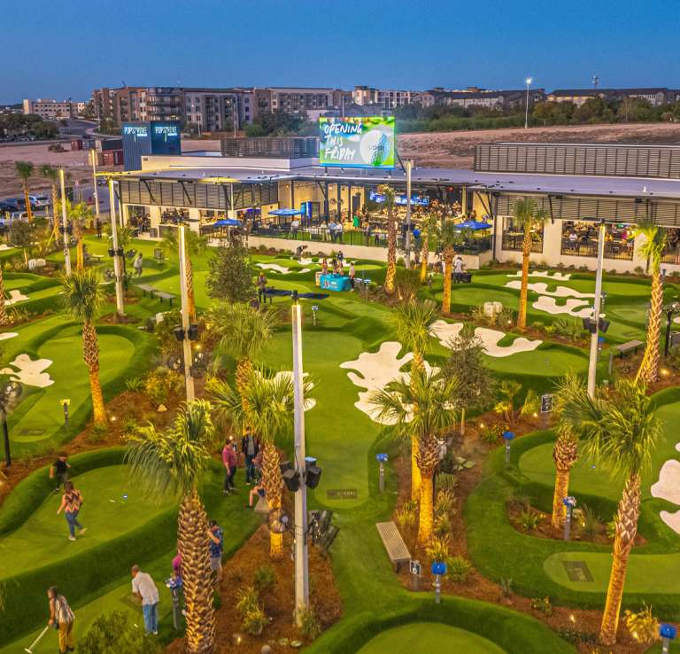 Overhead view of mini golf course with sand traps and palm trees.