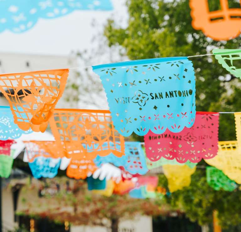Colorful papel picado with "Visit San Antonio" cut out.