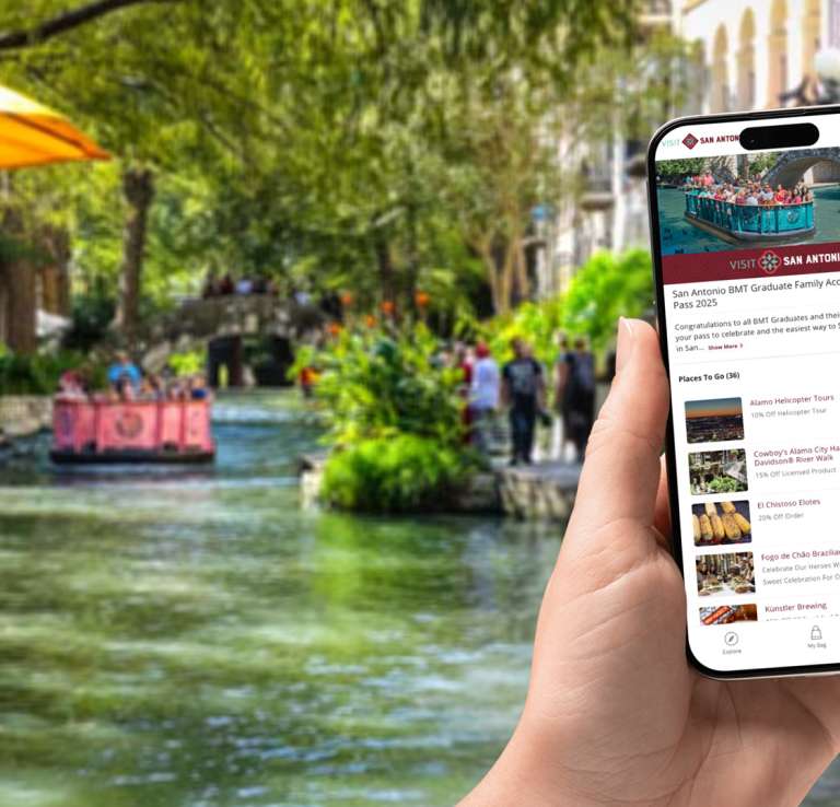Hand holding a phone with BMT Graduate Access Pass app screen visible.