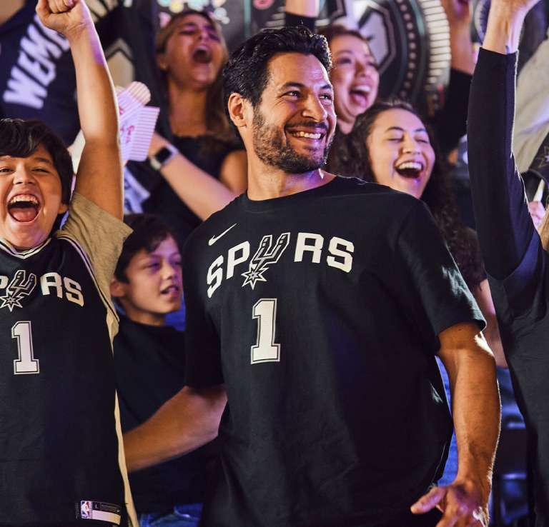 Fans cheering at game wearing Spurs shirts and jerseys