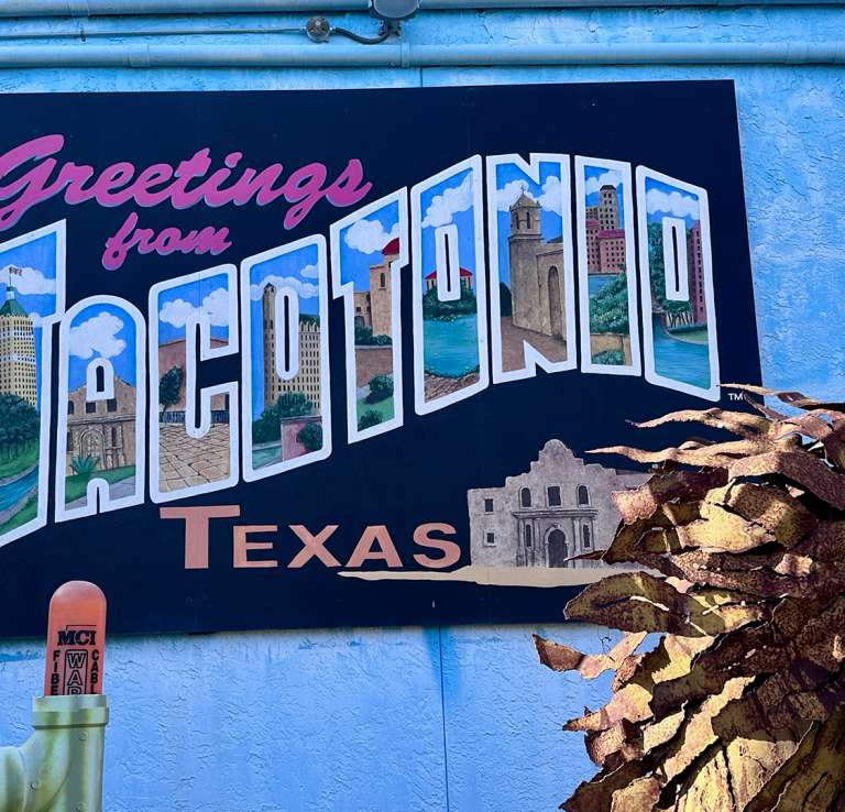 colorful mural of postcard that reads "Greetings from Tacotonio, Texas"