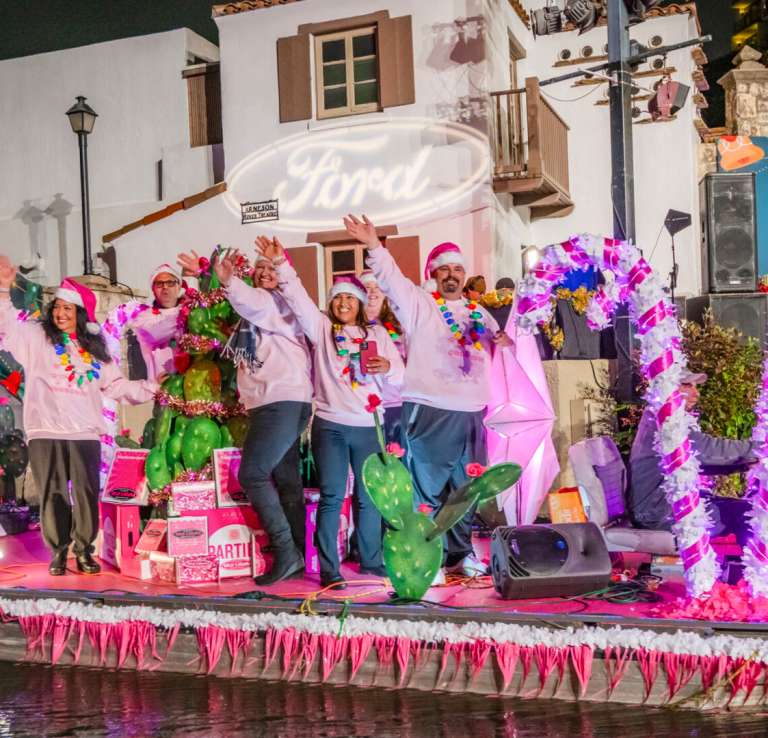 River barge at Ford Holiday River Parade with pink and white candy canes and people dressed in pink sweaters.
