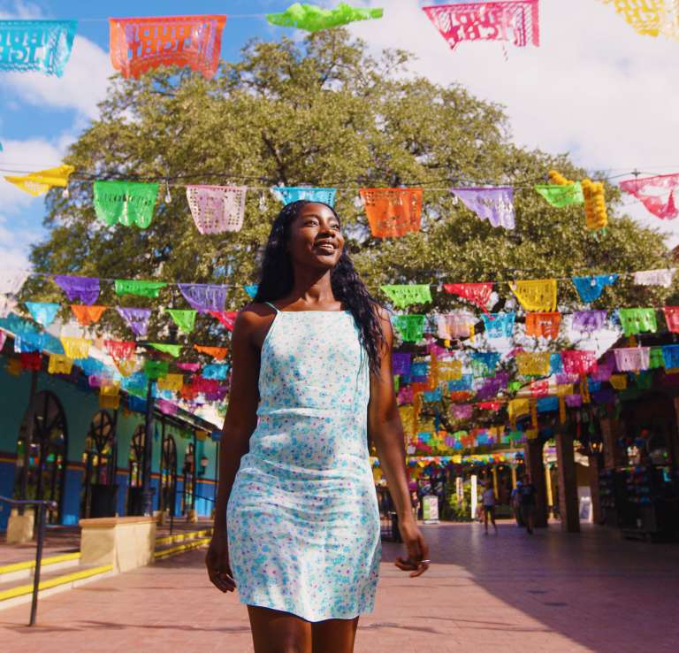 Woman walking through Historic Market Square with. papel picado in background.