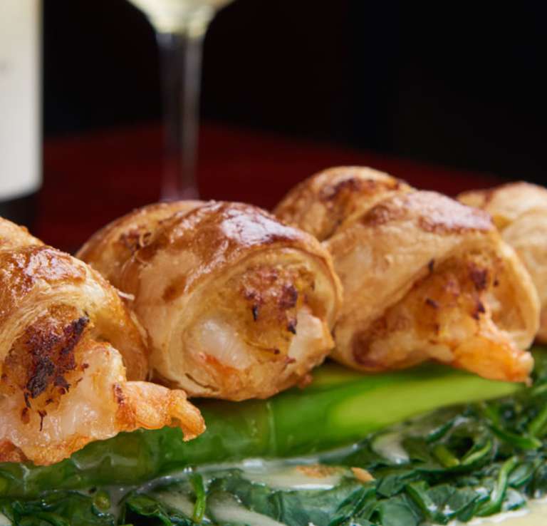 Wrapped shrimp over greens with lemon garnish