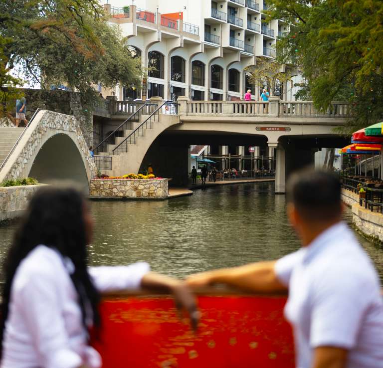 Couple on river barge facing bridge on River Walk