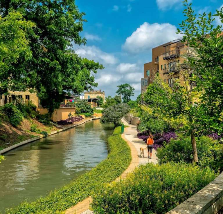 Woman walking along river bank at Museum Reach portion of the San Antonio River Walk
