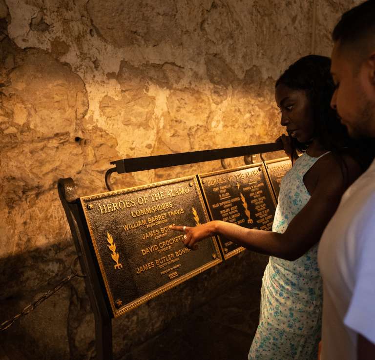 Man and woman looking at Alamo Heroes plaque