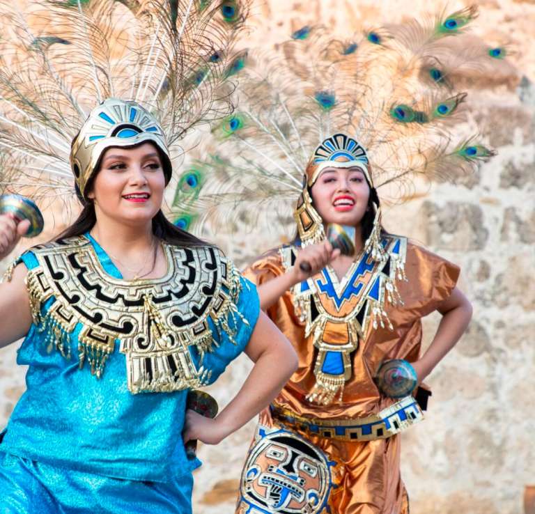 Two women in native dress in front of San Antonio Missions.