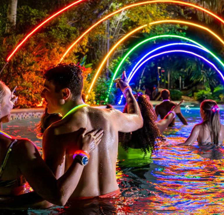 People wading under colorful lights at night.