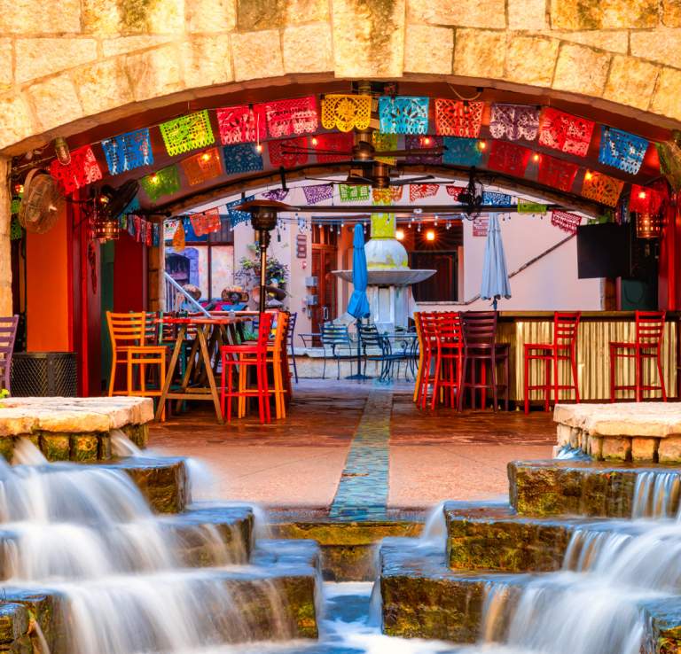 Arches and waterfall at Casa Rio with colorful papel picado in background.