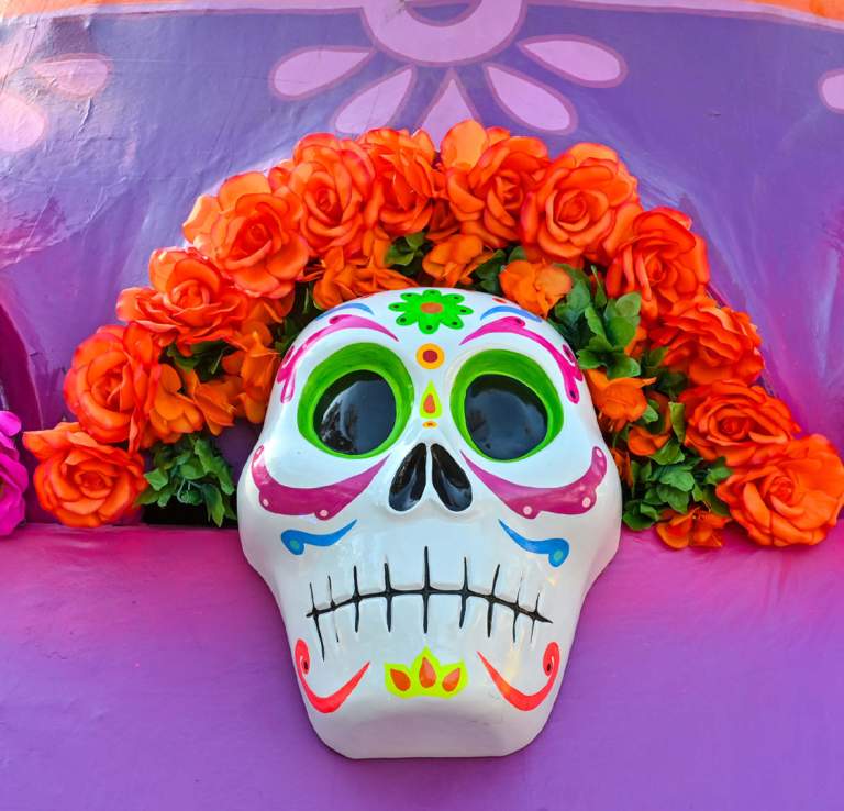 Brightly colored sugar skills with pink and orange flowers aranged around their heads at La Villita in San Antonio.