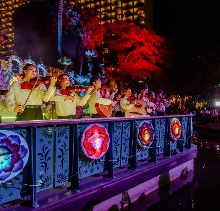 Mariachi band members on a river barge drifting in the Day of the Dead River Parade.