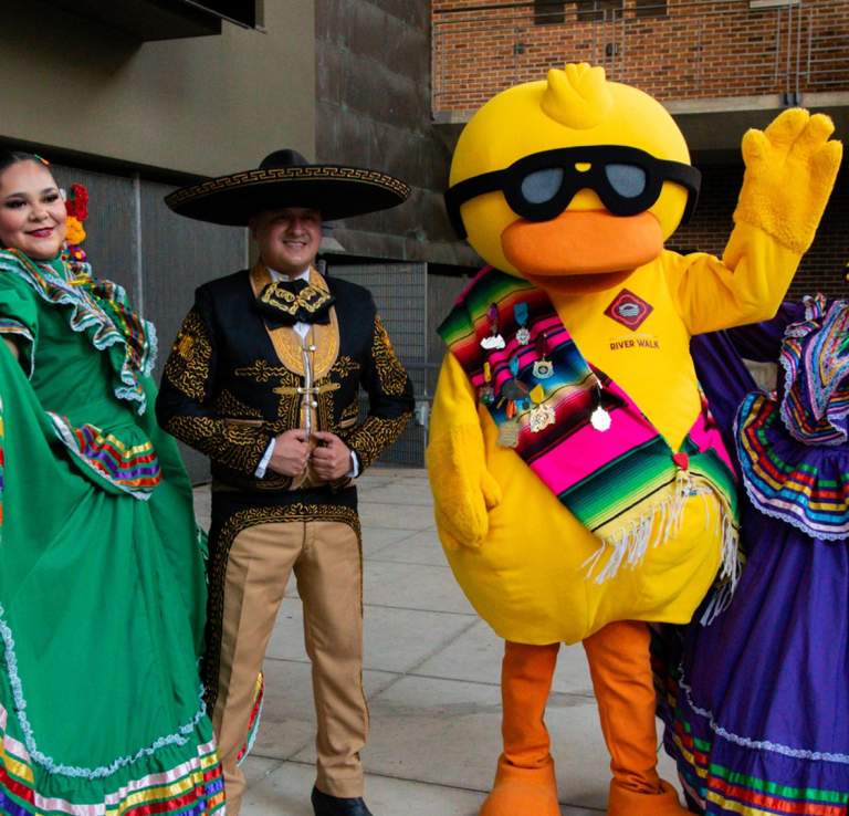 San Antonio River Walk mascot, Timmy Duckin, posing with folklorico dancers in San Antonio.
