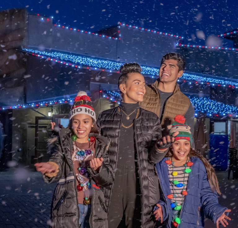 Family laughing with snow falling at San Antonio Zoo's Zoo Lights.