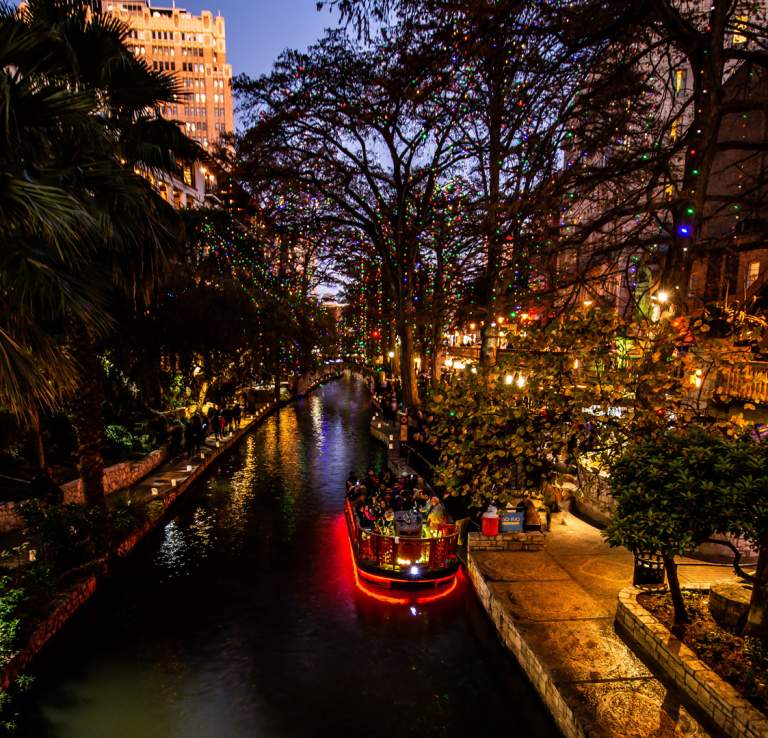River Walk lit up with holiday lights and river barge
