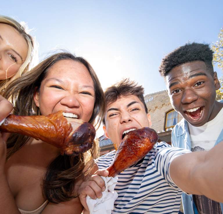 Group of friends taking a selfie and eating turkey legs.